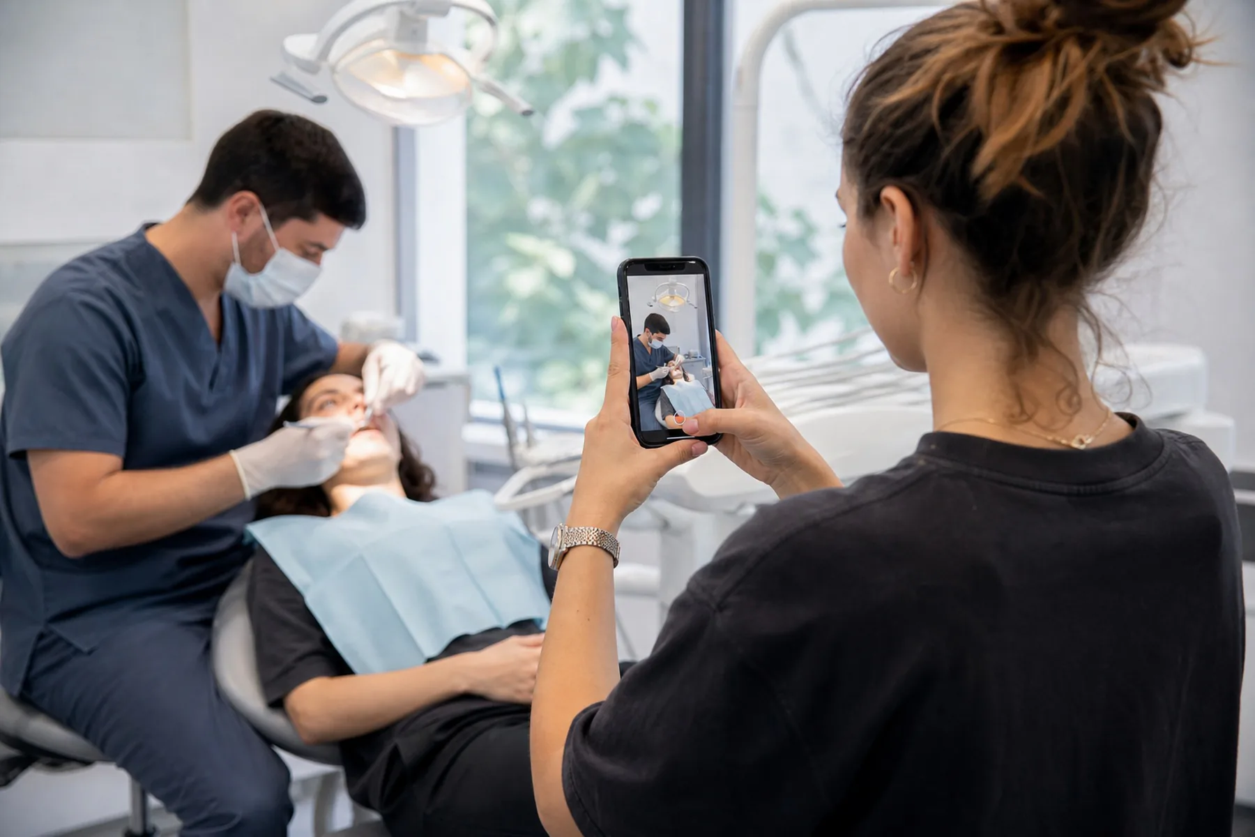Creadora de contenido grabando con un celular vertical un procedimiento en una clínica odontológica
